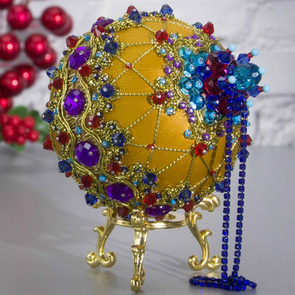Close-up Detail of Scheherazade Handmade Satin Ornament -Festive mustard-colored ball with purple rhinestones, sparkling gold trim, sequins, indigo rhinestone chain, and metallic cord. (Gold) 