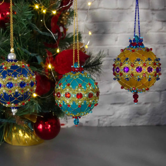 Collection of bright Sequin Satin Ornaments Scheherazade in blue and mustard colors with Christmas Tree in the background.