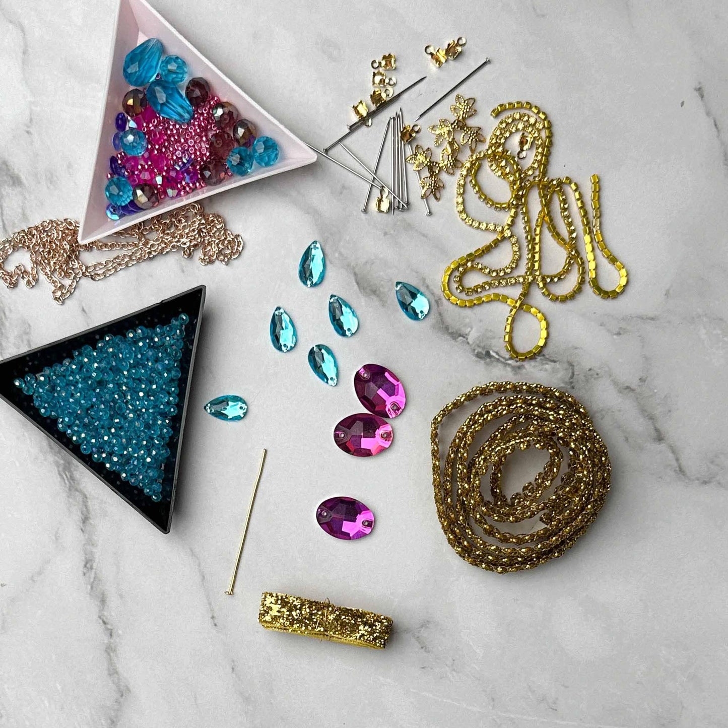 Materials to make Christmas Beaded Ornament by pinning glass rhinestones, gold braided trim, and crystal beads. to a satin ball. (Indigo).