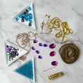 Load image into Gallery viewer, Materials to make Christmas Beaded Ornament by pinning glass rhinestones, gold braided trim, and crystal beads. to a satin ball. (Sky Blue).
