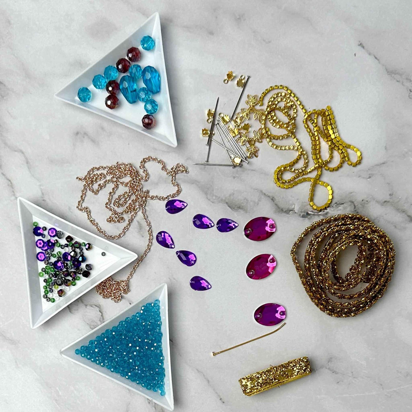 Materials to make Christmas Beaded Ornament by pinning glass rhinestones, gold braided trim, and crystal beads. to a satin ball. (Sky Blue).