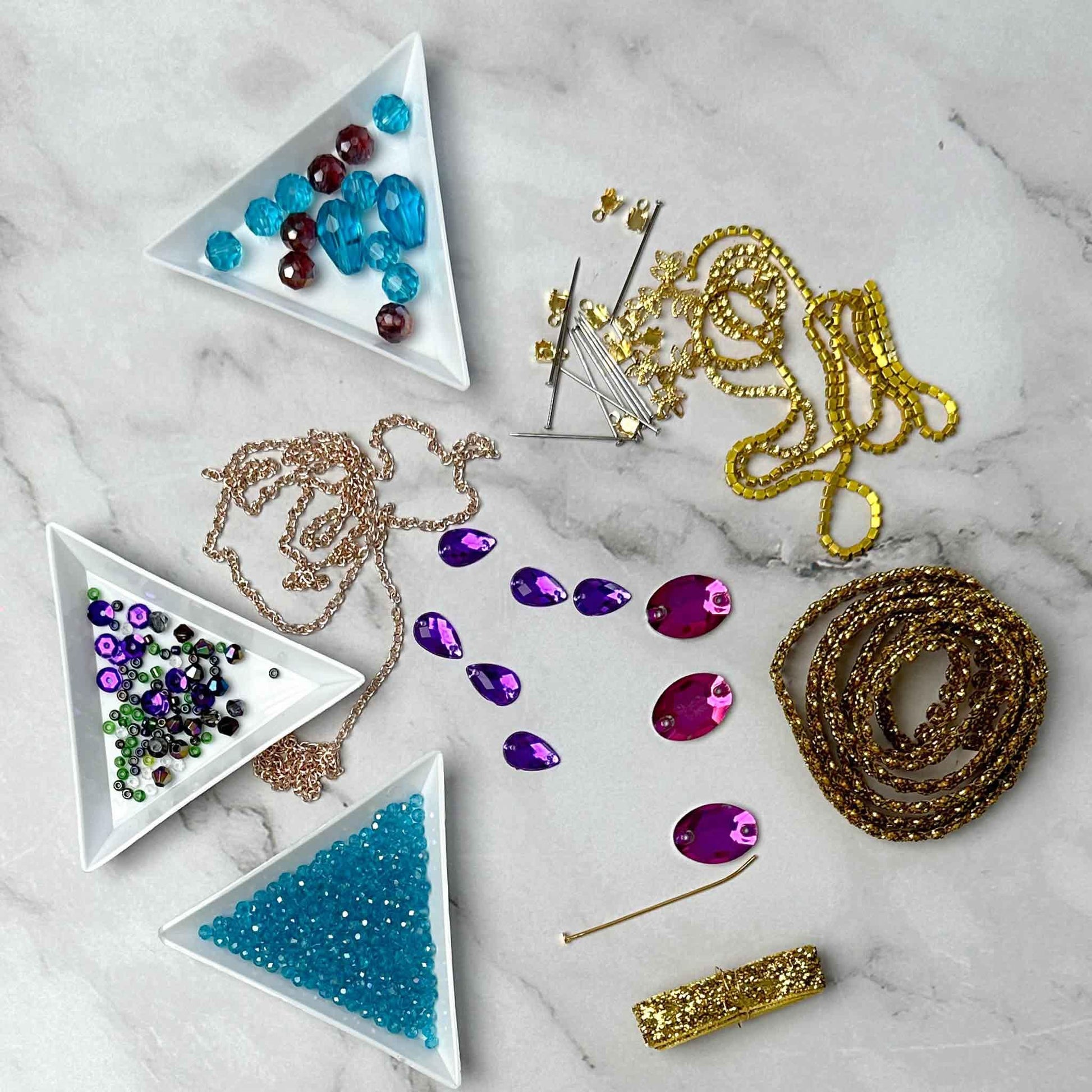 Materials to make Christmas Beaded Ornament by pinning glass rhinestones, gold braided trim, and crystal beads. to a satin ball. (Sky Blue).