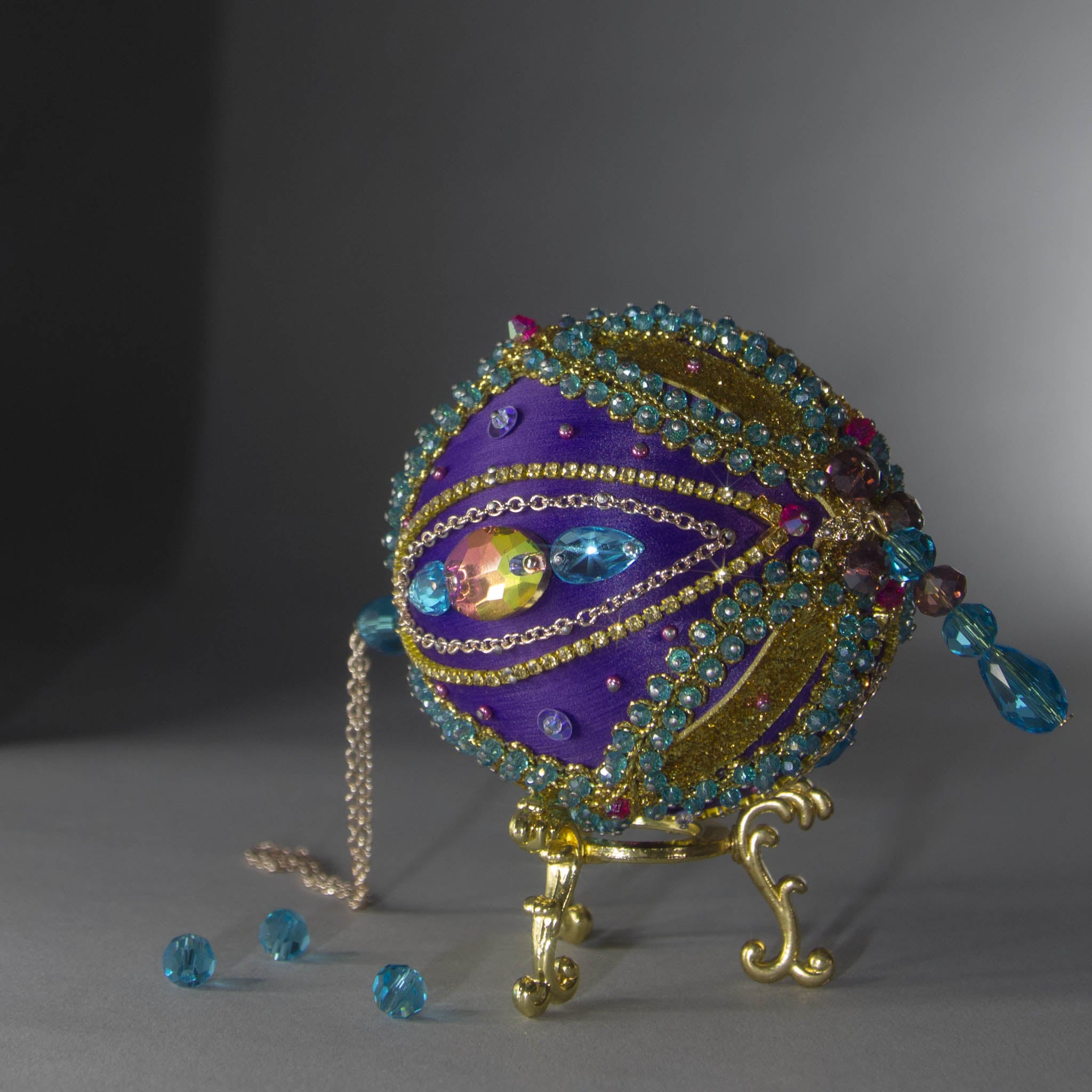 Christmas Beaded Ornament Kit Ball embellished with glass rhinestones, gold braided trim, and crystal beads. Bottom detail. (Indigo).