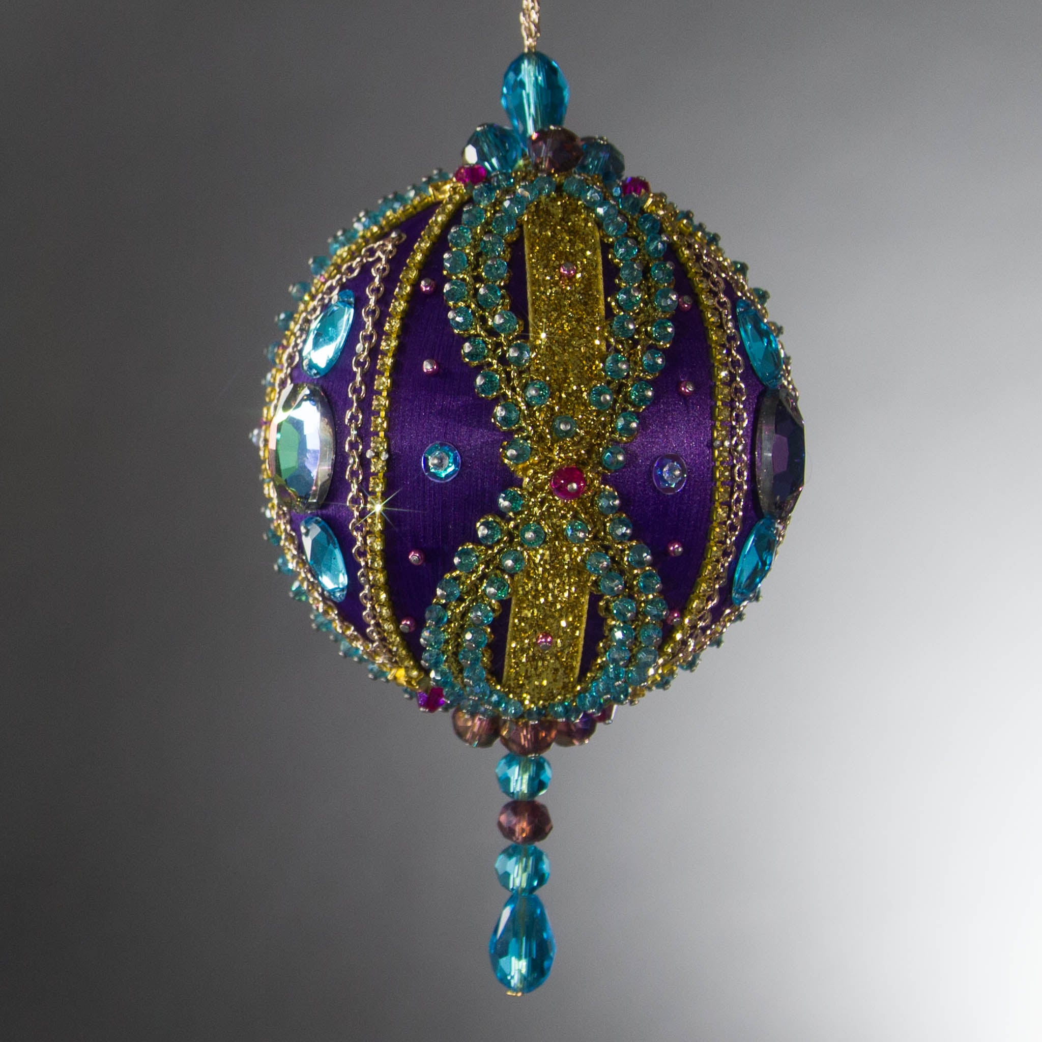 Christmas Beaded Ornament Kit Ball embellished with glass rhinestones, gold braided trim, and crystal beads. Front. (Indigo).