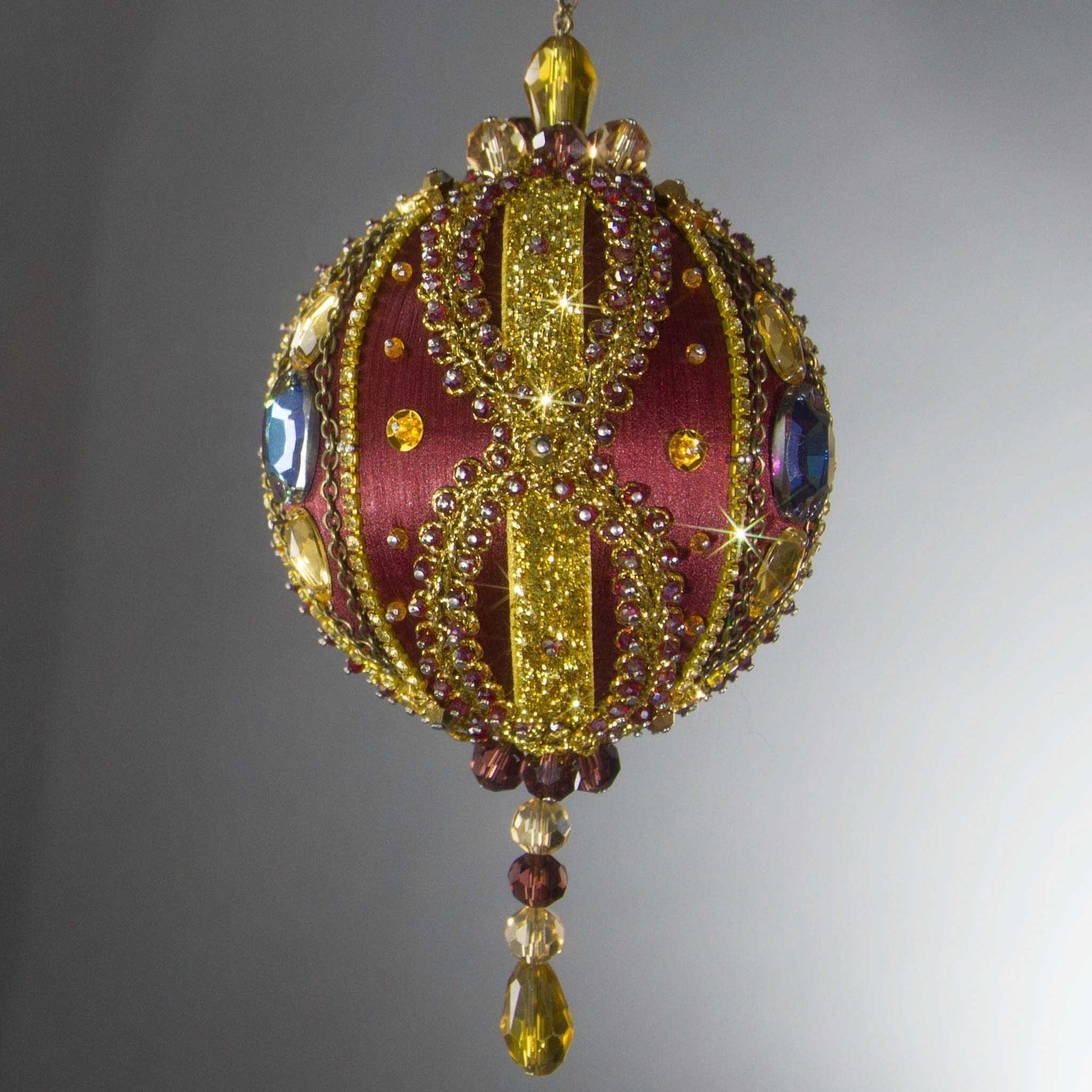 Christmas Beaded Ornament Kit Ball embellished with glass rhinestones, gold braided trim, and crystal beads. Front. (Maroon).