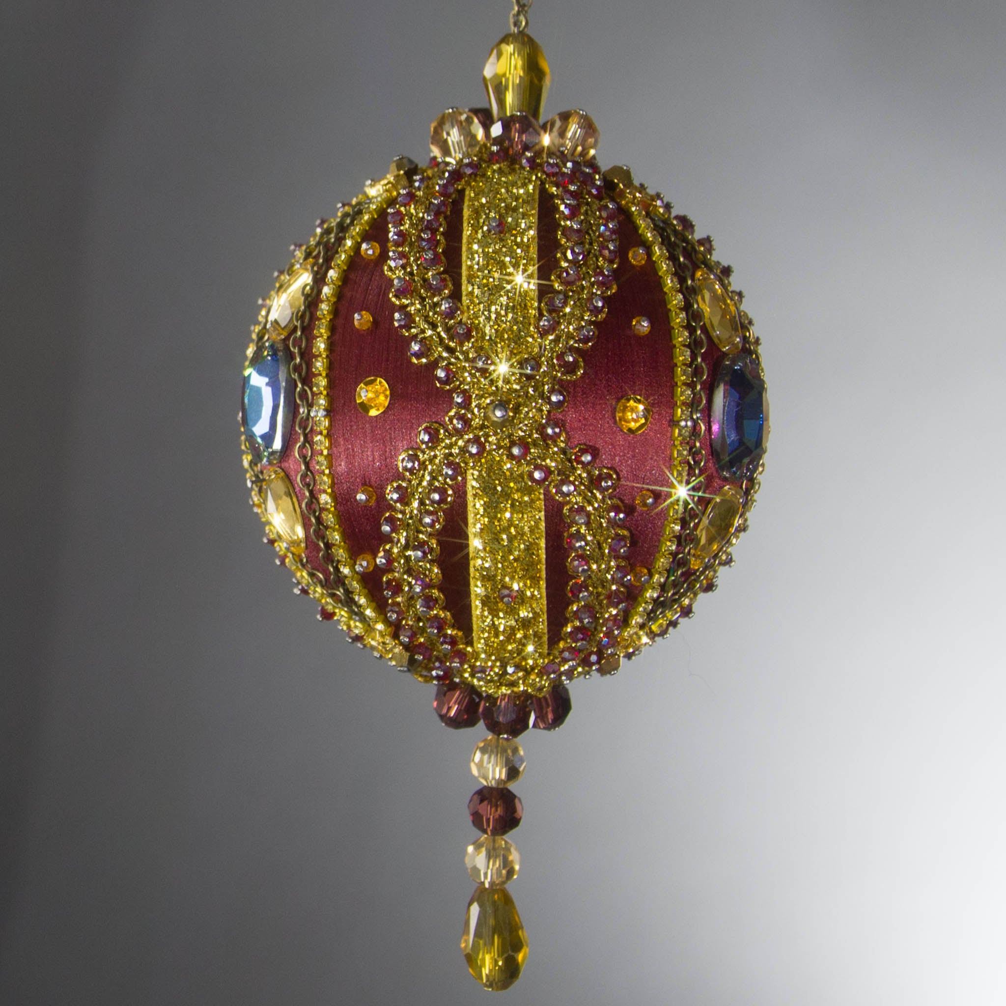 Christmas Beaded Ornament Kit Ball embellished with glass rhinestones, gold braided trim, and crystal beads. Front. (Maroon).