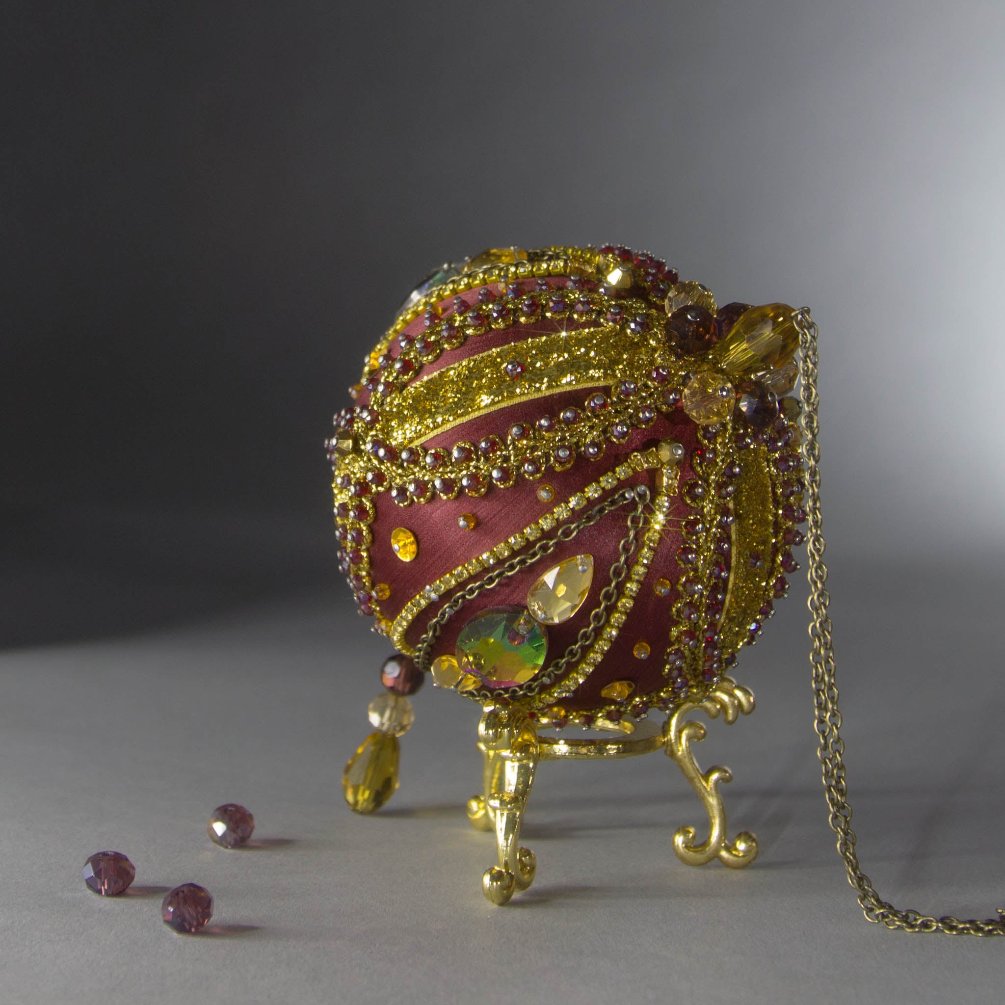 Christmas Beaded Ornament Kit Ball embellished with glass rhinestones, gold braided trim, and crystal beads. Top detail. (Maroon).