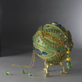 Load image into Gallery viewer, Christmas Beaded Ornament Ball embellished with large glass color-shifting rhinestones, gold braided trim, and crystal beads. Bottom detail. (Olive).
