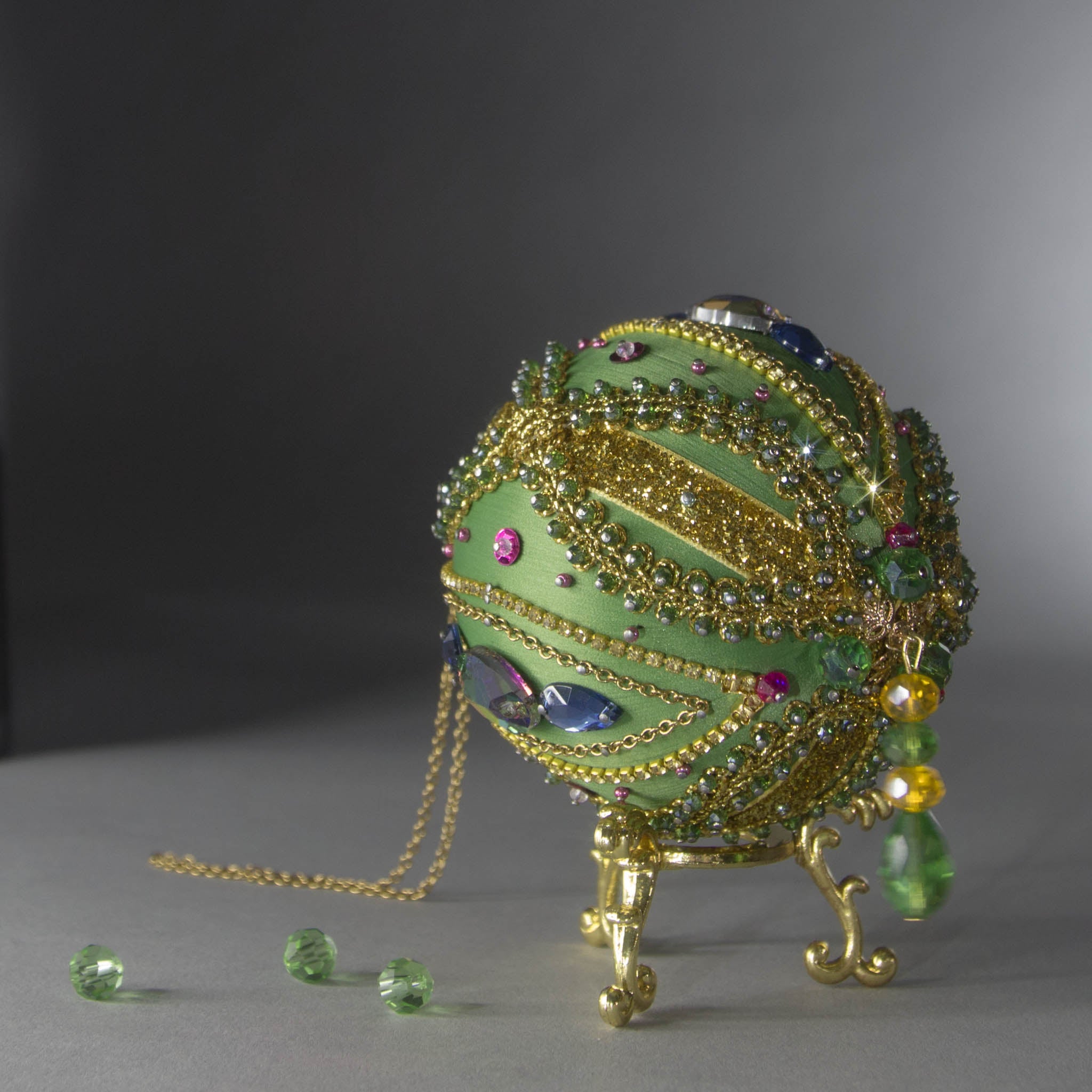Christmas Beaded Ornament Ball embellished with large glass color-shifting rhinestones, gold braided trim, and crystal beads. Bottom detail. (Olive).
