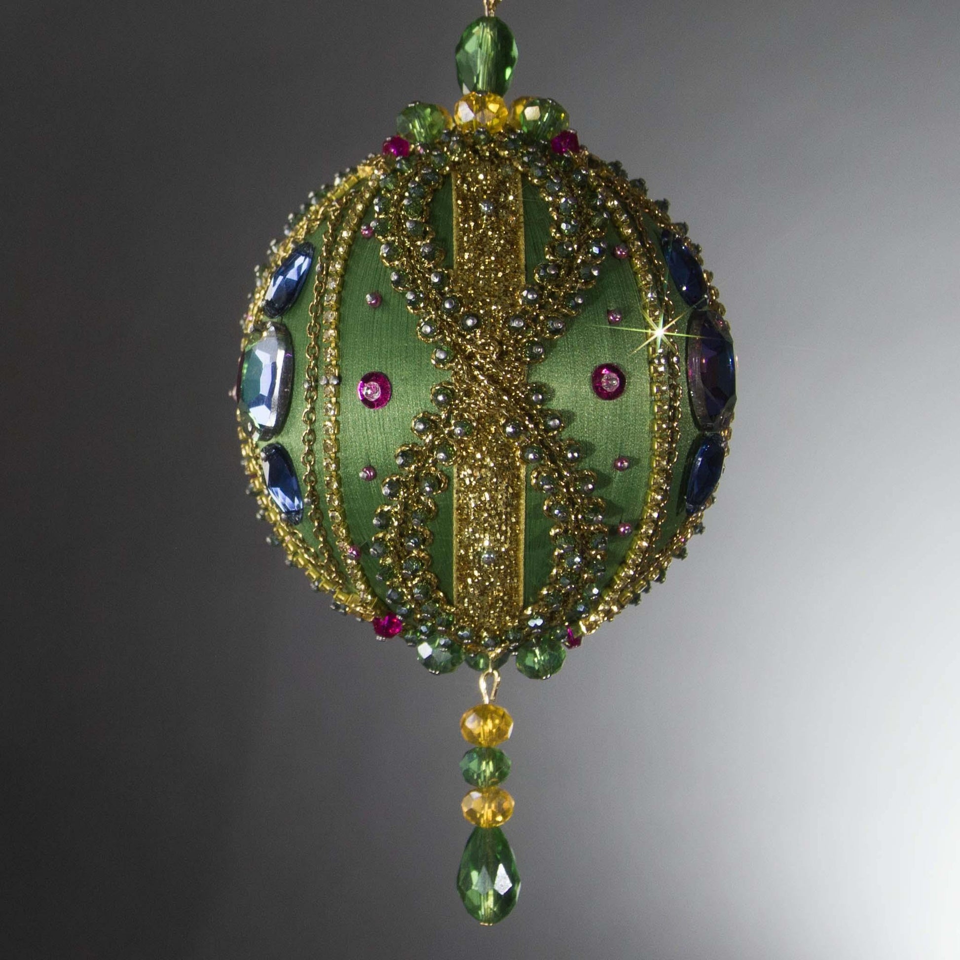 Christmas Beaded Ornament Ball embellished with large glass color-shifting rhinestones, gold braided trim, and crystal beads. Side view. (Olive).