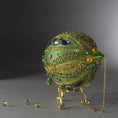 Load image into Gallery viewer, Christmas Beaded Ornament Ball embellished with large glass color-shifting rhinestones, gold braided trim, and crystal beads. Top detail. (Olive).
