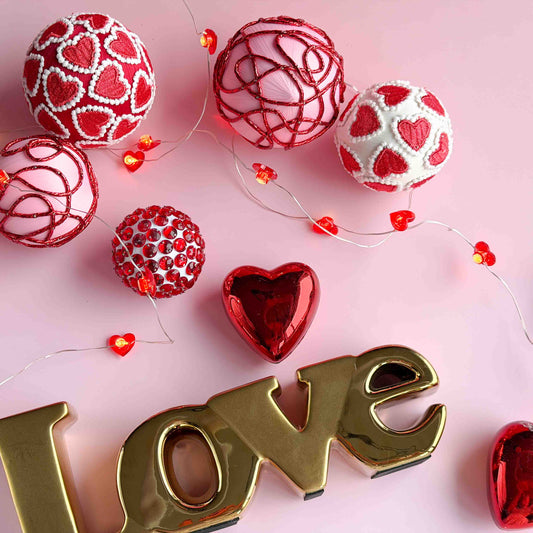 Decorative items with red hearts and gold 'LOVE' letters on a pink background