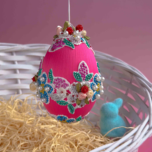 Decorative pink Easter egg with floral embroidery and beads on a pink background. (Deep Pink) 