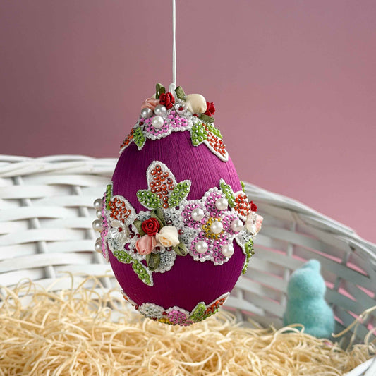 Easter egg with floral embellishments on a pink background.  (Purple) 