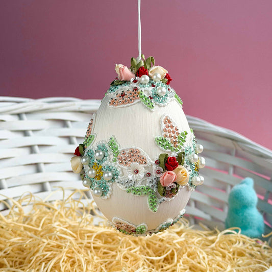 Festive Easter egg with flowers and beads on a pink background.  (Old Lace) 