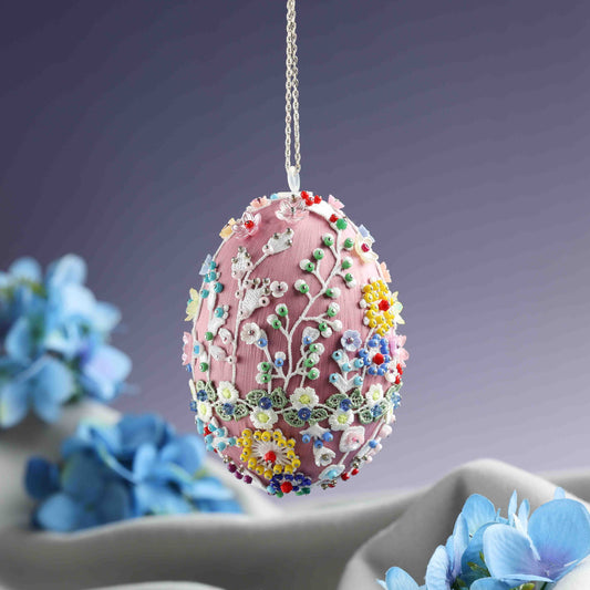 Decorative Easter egg with floral patterns hanging above blue flowers on a gradient background.  (Pale Violet Red)