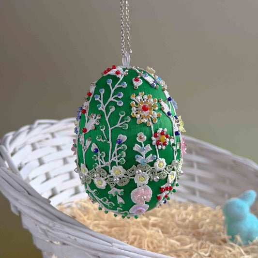 Decorative Easter egg with floral patterns on a white basket with straw and a small blue bunny. (Green)
