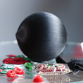Load image into Gallery viewer, Black satin ball close-up on a reflective surface with decorative items around. (Black)
