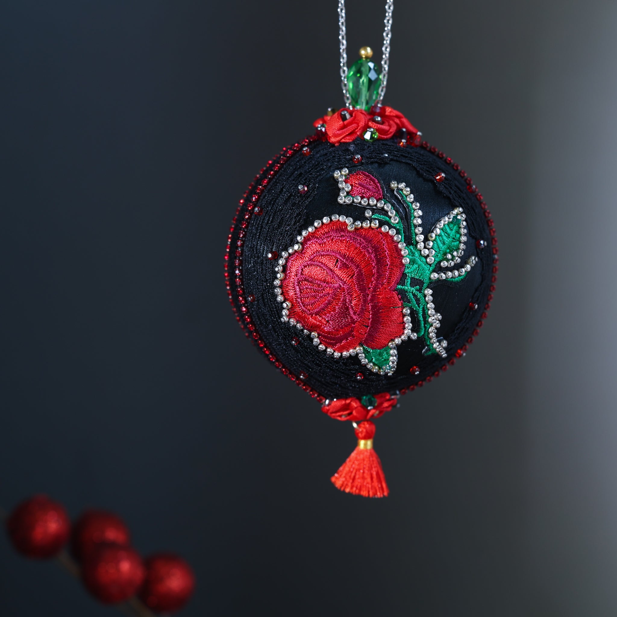Decorative Christmas ornament with embroidered red rose on a dark background. (Black)