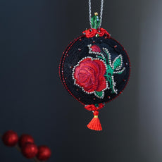 Decorative Christmas ornament with embroidered red rose on a dark background. (Black)