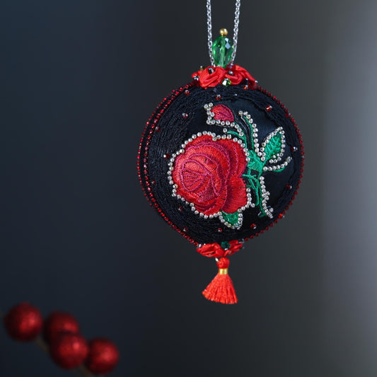 Decorative Christmas ornament with embroidered red rose on a dark background. (Black)