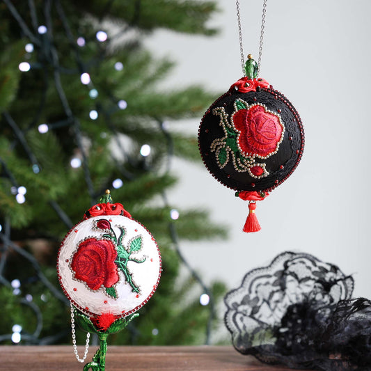 Decorative Christmas ornaments with red roses on a blurred Christmas tree background.