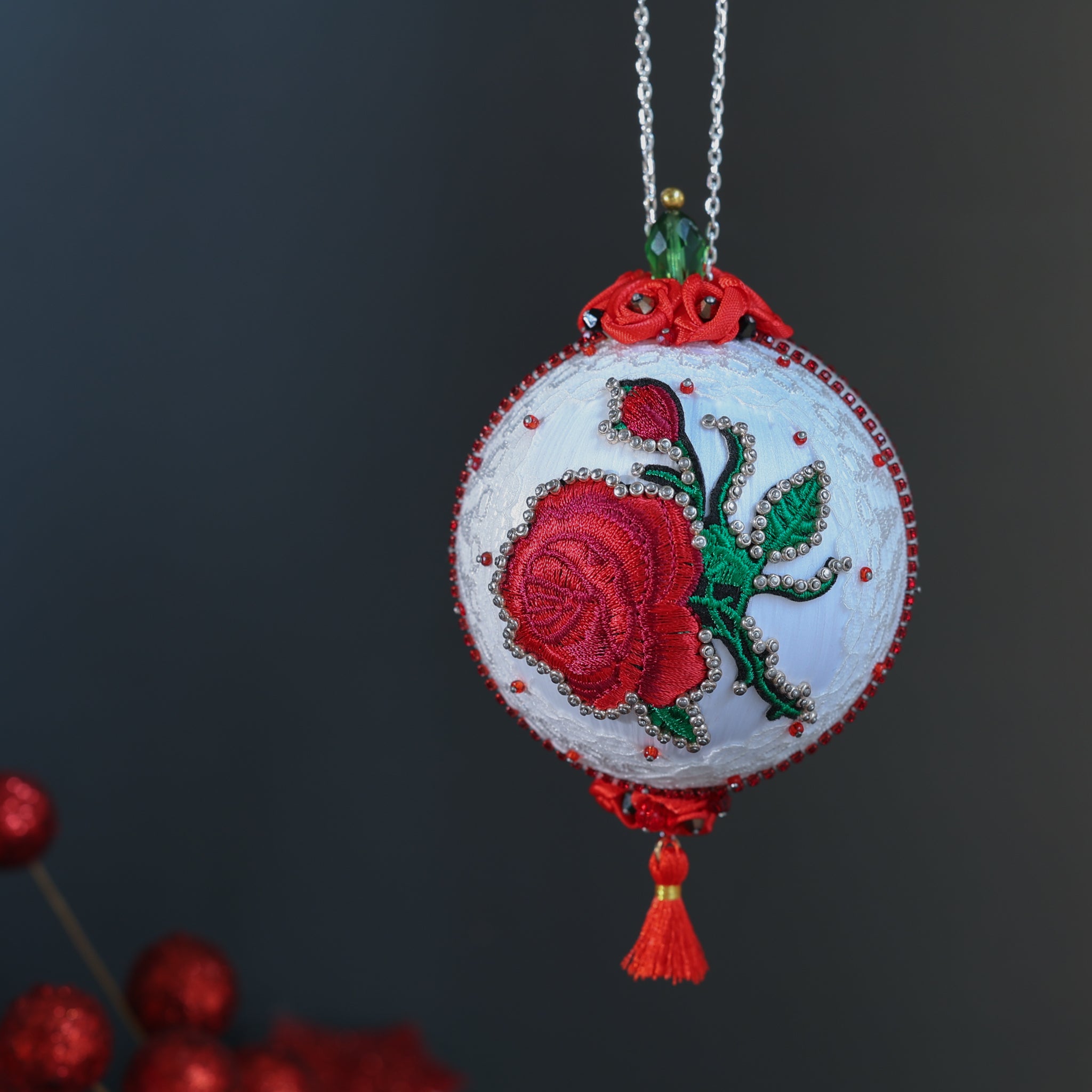 White festive decorative Christmas ornament with embroidered red rose on a dark background. (White)