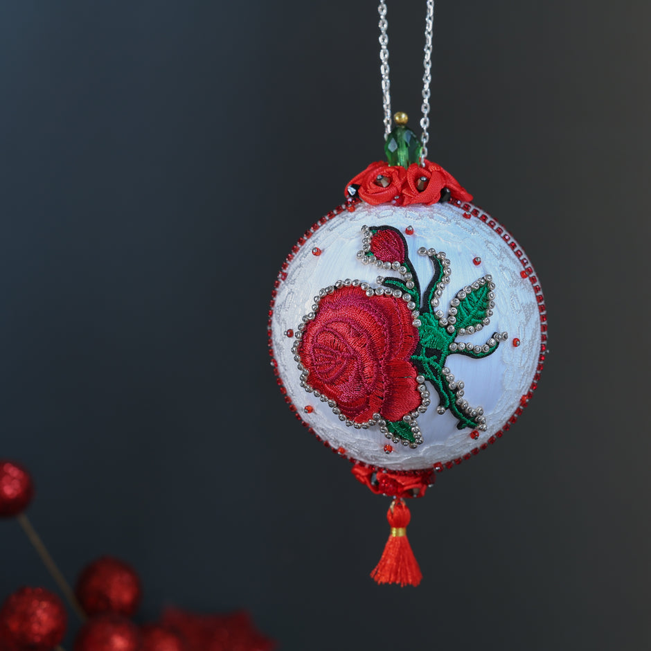White festive decorative Christmas ornament with embroidered red rose on a dark background. (White)