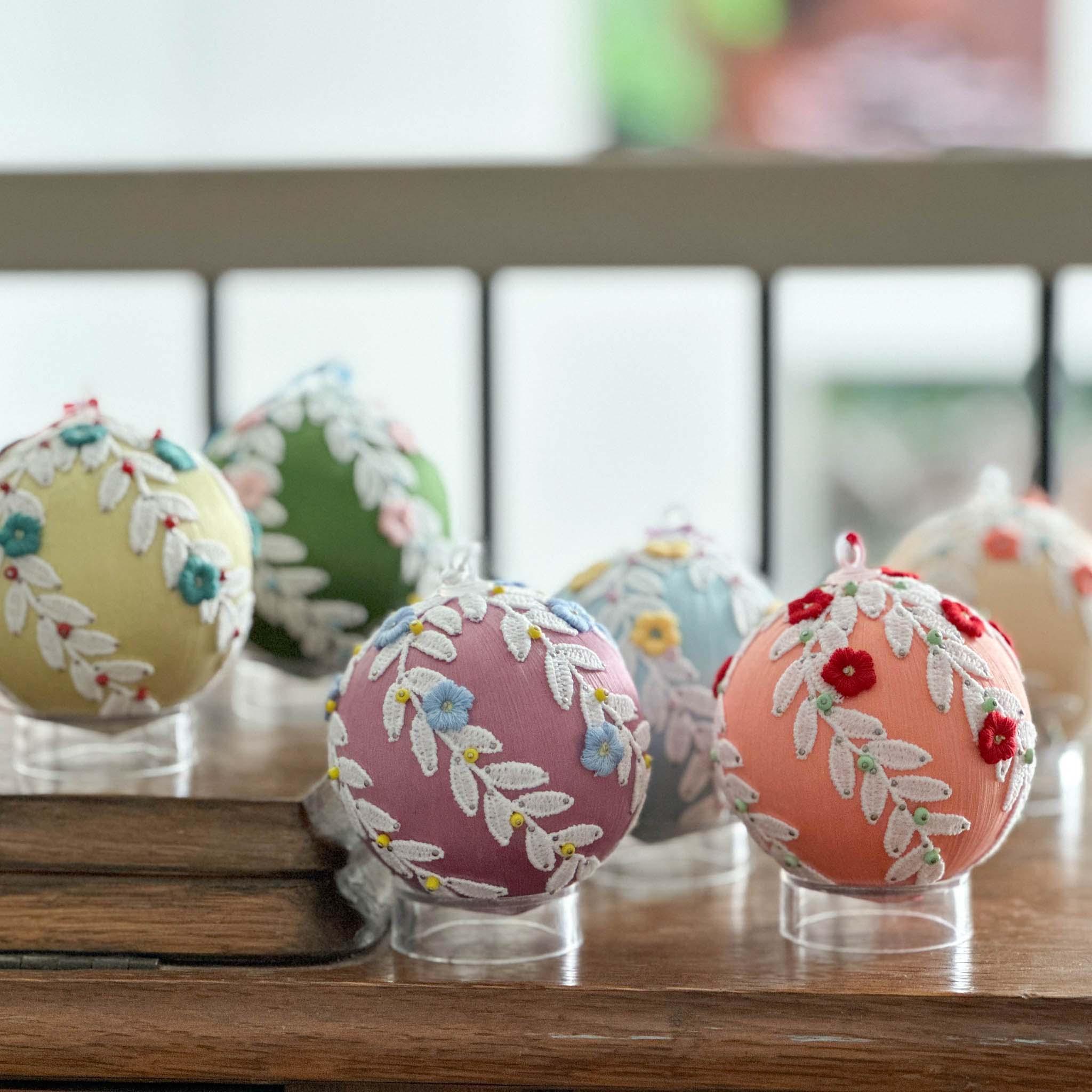 A collection of handmade retro style beaded push pin ornaments on a wooden surface on a blurred background.