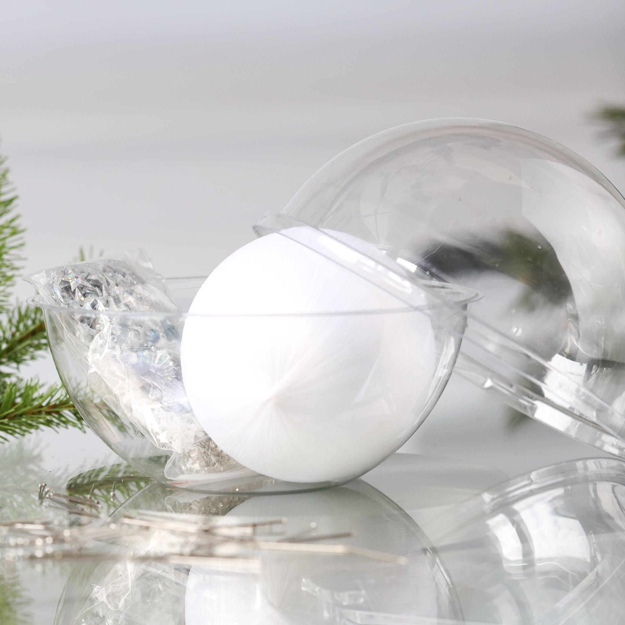 Christmas Push Pin Ornament Kit New Year Star in a clear plastic packaging includes a white satin ball, and a bag with star sequins, pictured with a holiday branch.  (White)