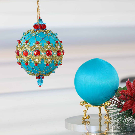 Push pin ornament kit showcasing a finished bright teal-colored handmade Christmas ornament with red rhinestones and a satin foam core for crafting another ornament. (Light Sea Green)
