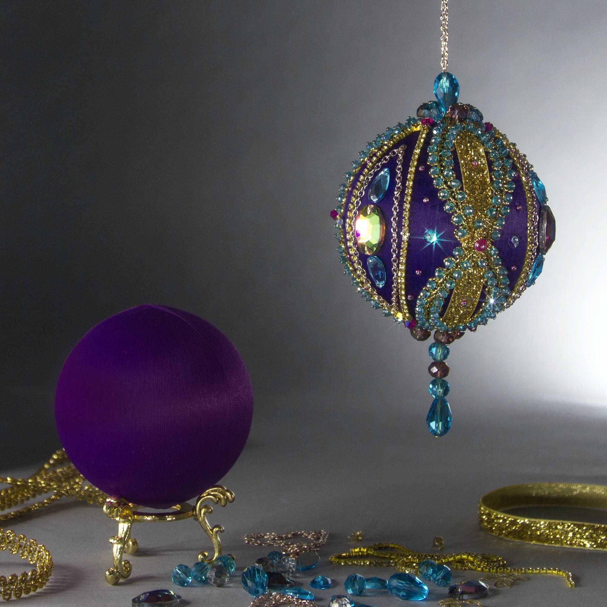 DIY Christmas Beaded Satin Ornament Kit showing a completed ball embellished with glass rhinestones, gold braided trim, and crystal beads, and a bare foam core ball wrapped in satin threads by Whim5seasons.