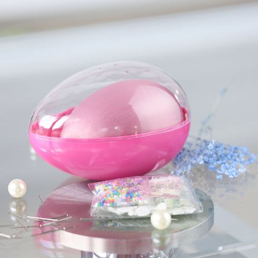 Decorative Easter egg push pin kit in an egg-shaped container with a clear lid with a small packet of beads on a reflective surface by Whim5seasons.