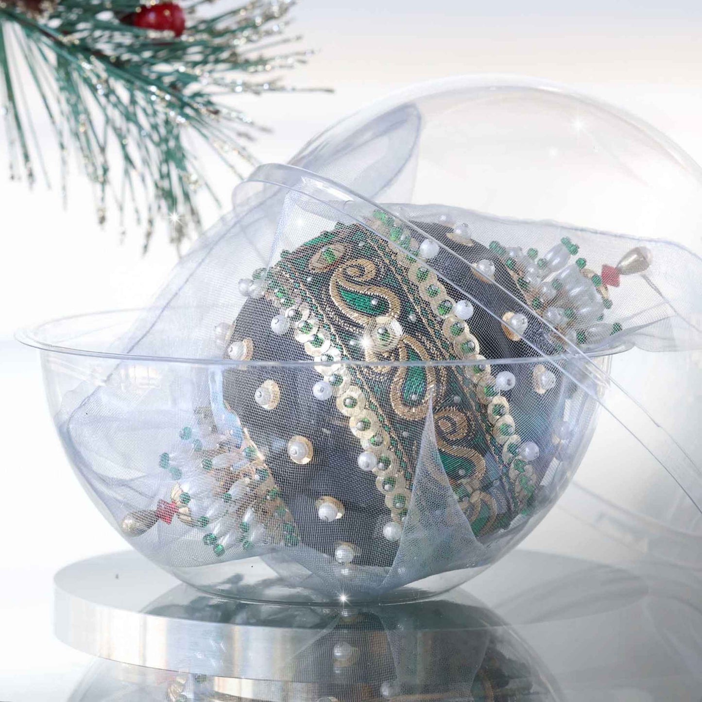 Handmade black retro Christmas beaded ornament with intricate design on a reflective surface in a clear storage box with an evergreen branch in the background by Whim5seasons.