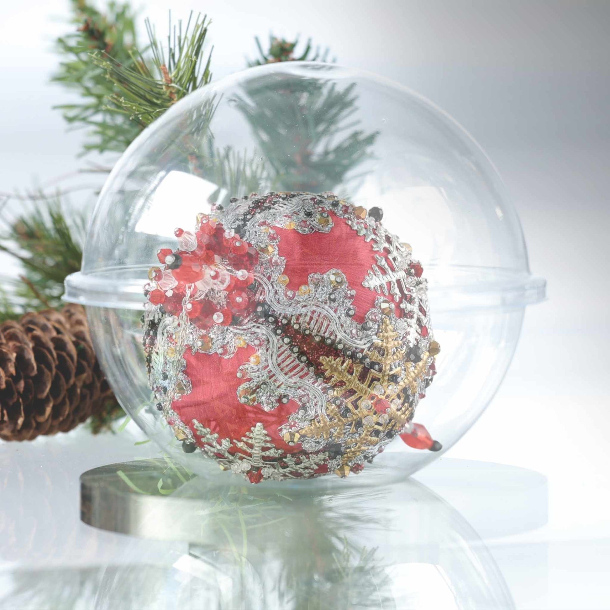 A close-up of a handmade push pin ornament with glass beads, and metallic trim on a satin ball in a clear round storage container by Whim5seasons.