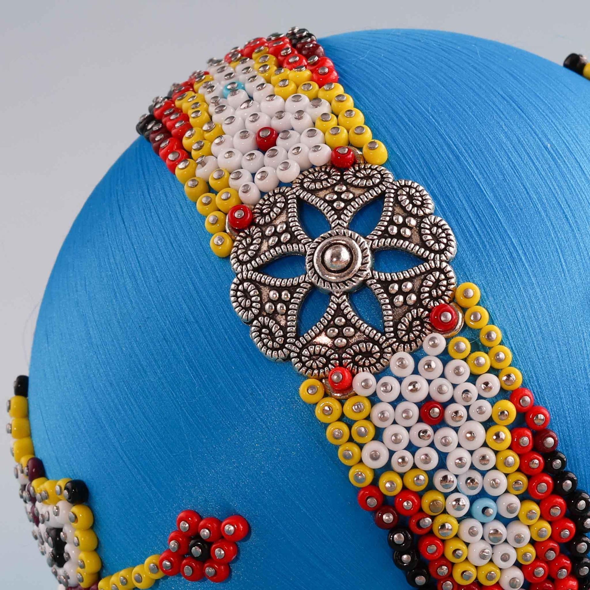 A close-up detail of a handmade colorful satin beaded ornament showing hundreds of seed beads pinned with dressmaker pins to a foam core by Whim5seasons. 