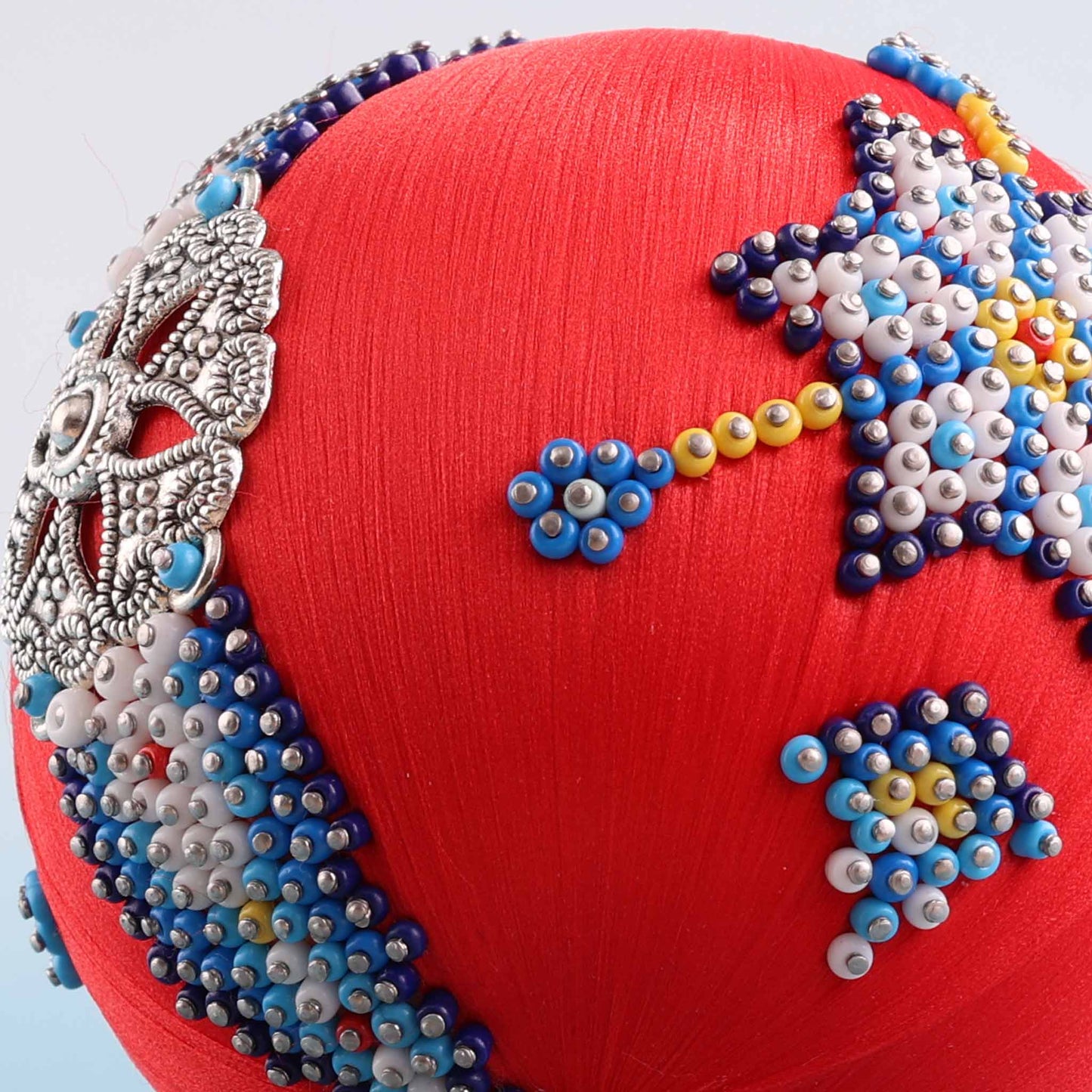 A close-up detail of a handmade push pin ornament showcasing indigenous style beadwork applied to a satin core with dressmaker pins by Whim5seasons.