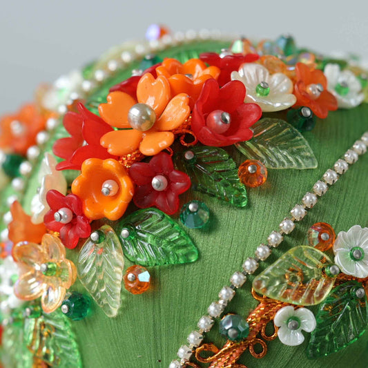 A close up detail of a Christmas handmade sequin & beaded ornament adorned with miniature flower charms, glass beads, and festive pearl rhinestone chain trims by Whim5seasons.