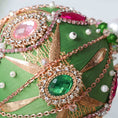 Load image into Gallery viewer, Close-up detail of a handmade beaded Christmas ornament with pink and green beades secured in place with dressmaker pins by Whim5seasons. (Olive)
