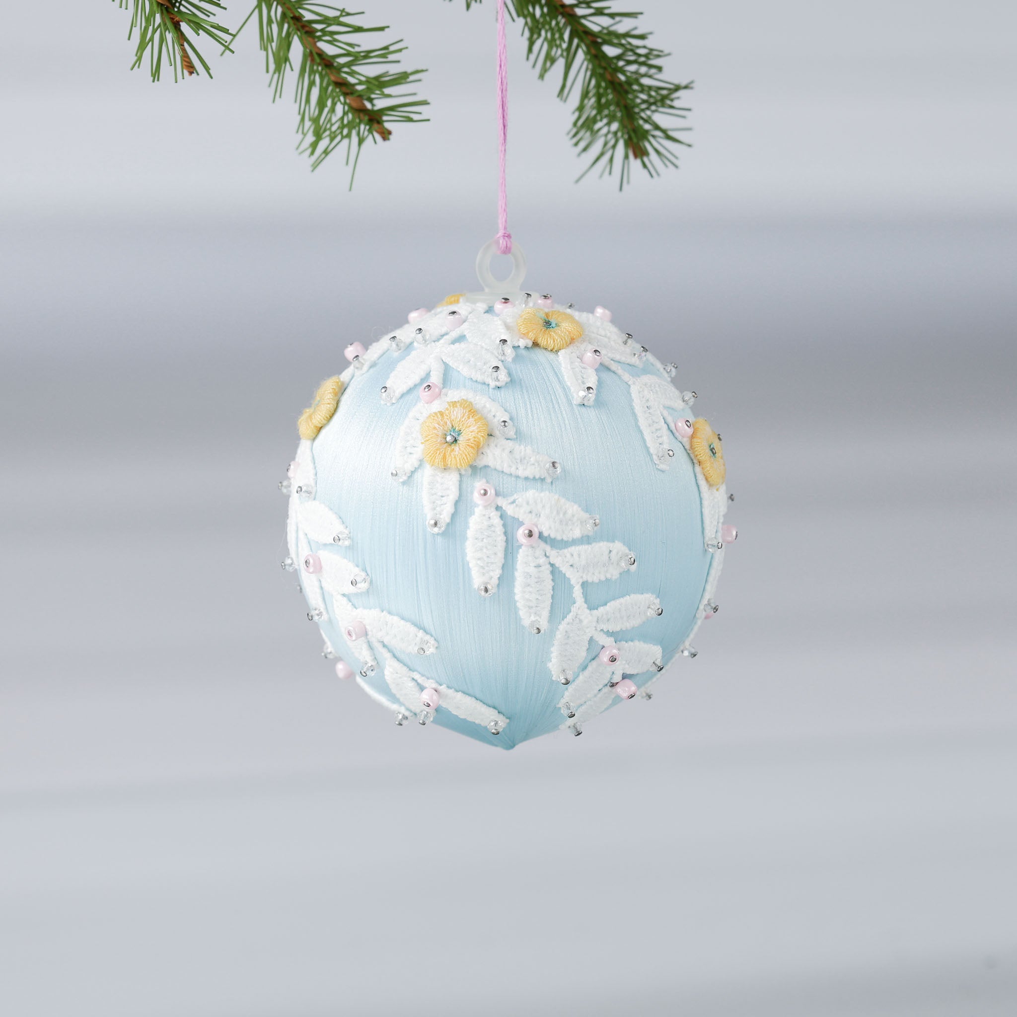 Handmade Mid-Century Style Beaded Christmas ornament  - a satin push pin core as a base, embellished with white lace trim, yellow embroidered flowers, and pink and clear beads, hanging on a pink string loop (Light Blue)