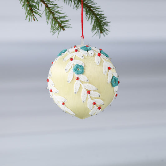 Handmade push pin beaded Christmas Ornament Ball embellished with embroidered flowers, white lace trim, and small clear beads hanging from a green evergreen branch. (Khaki)