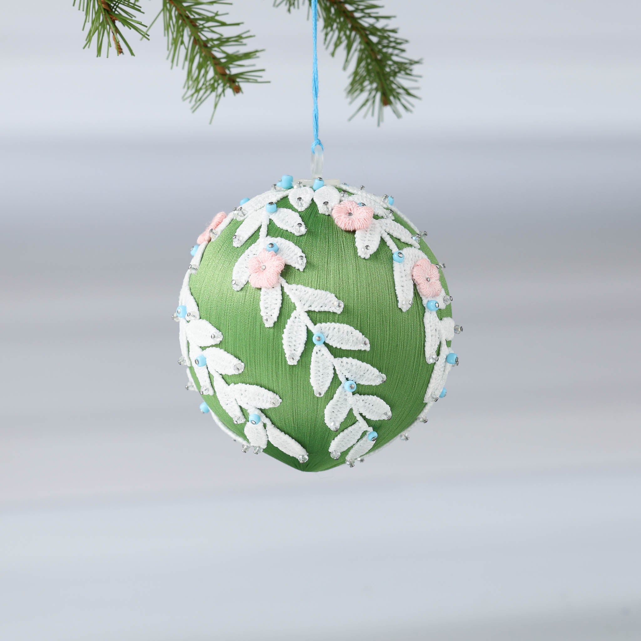 Handmade olive green Christmas or Easter Beaded push pin Ornament Ball embellished with flowers, white trim, and beads hanging on a blue string. (Olive)