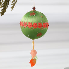 A Handmade Push Pin Ornament in olive featuring a rust colored maple ribbon trim pinned to a satin foam core with dressmaker pins, and some acrylic maple leaf charms, and clear seed beads. (Olive)