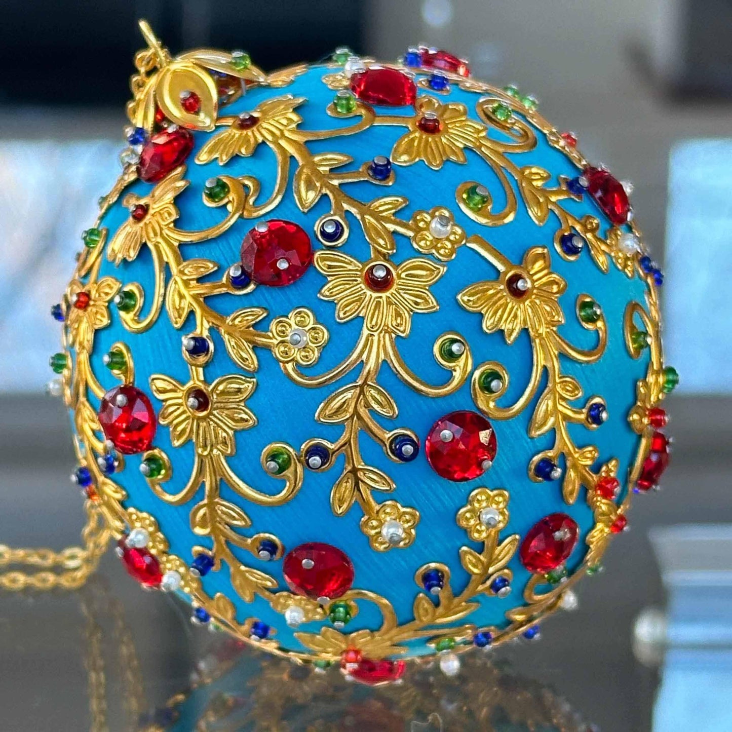 Quam Handmade Ornament  from Whim5seasons makes a unique gift - rich sky blue color, gold accents, festive design, on a reflective table.