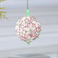 Load image into Gallery viewer, Handmade sequin & beaded pink satin ornament featuring flower trim hanging in front of gray background and holiday greenery by Whim5seasons.
