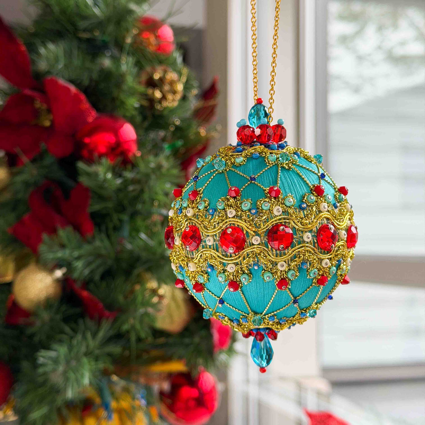 Handmade Push Pin Christmas ornament with blue, red, and gold accents on a Christmas tree in front of a window by Whim5seasons.