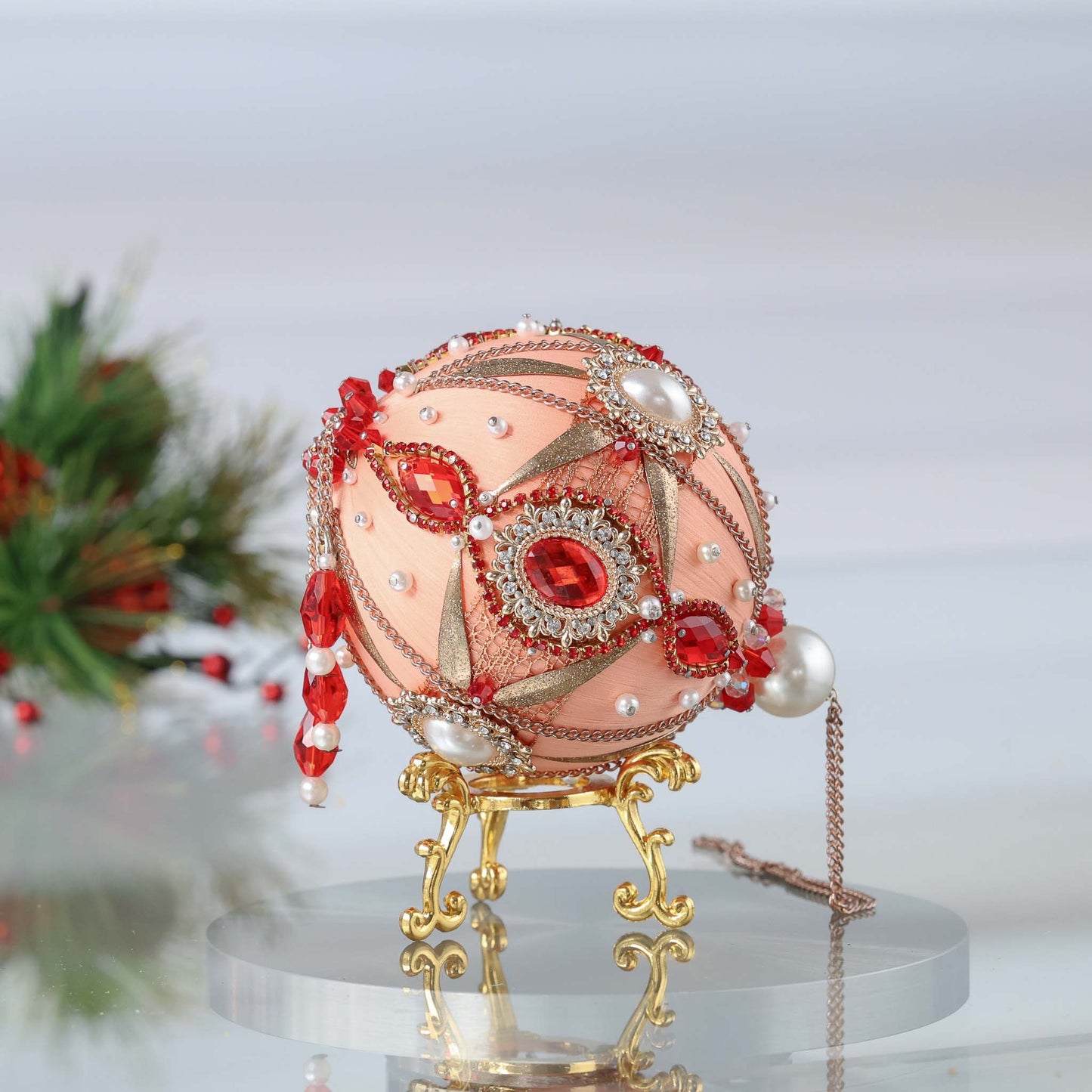 Decorative push pin ornament with red and gold embellishments on a stand against a blurred background by Whim5seasons. (Coral)