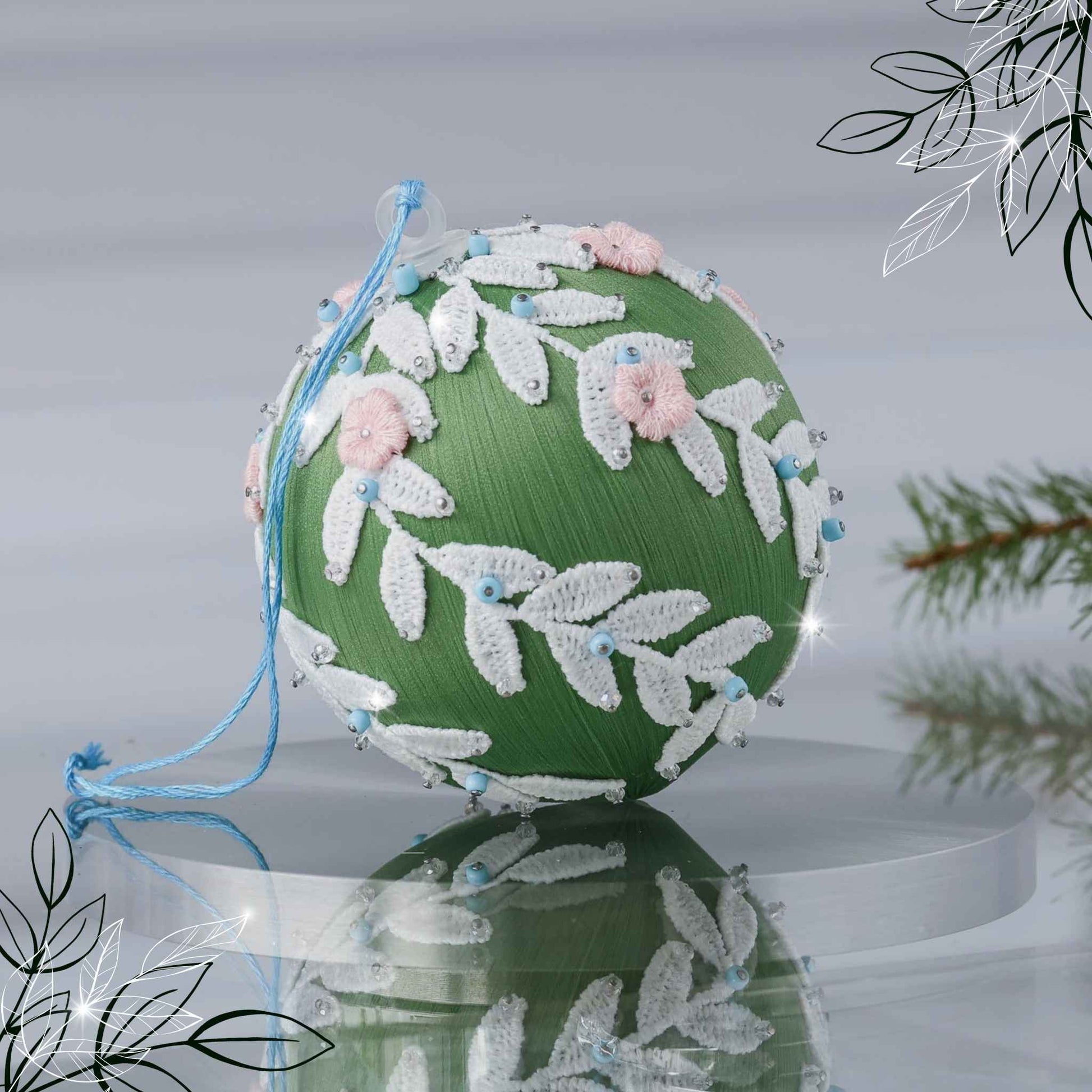 Handmade olive green Christmas or Easter Beaded push pin Ornament Ball embellished with flowers, white trim, and beads on a reflective surface with holiday greenery by Whim5seasons.