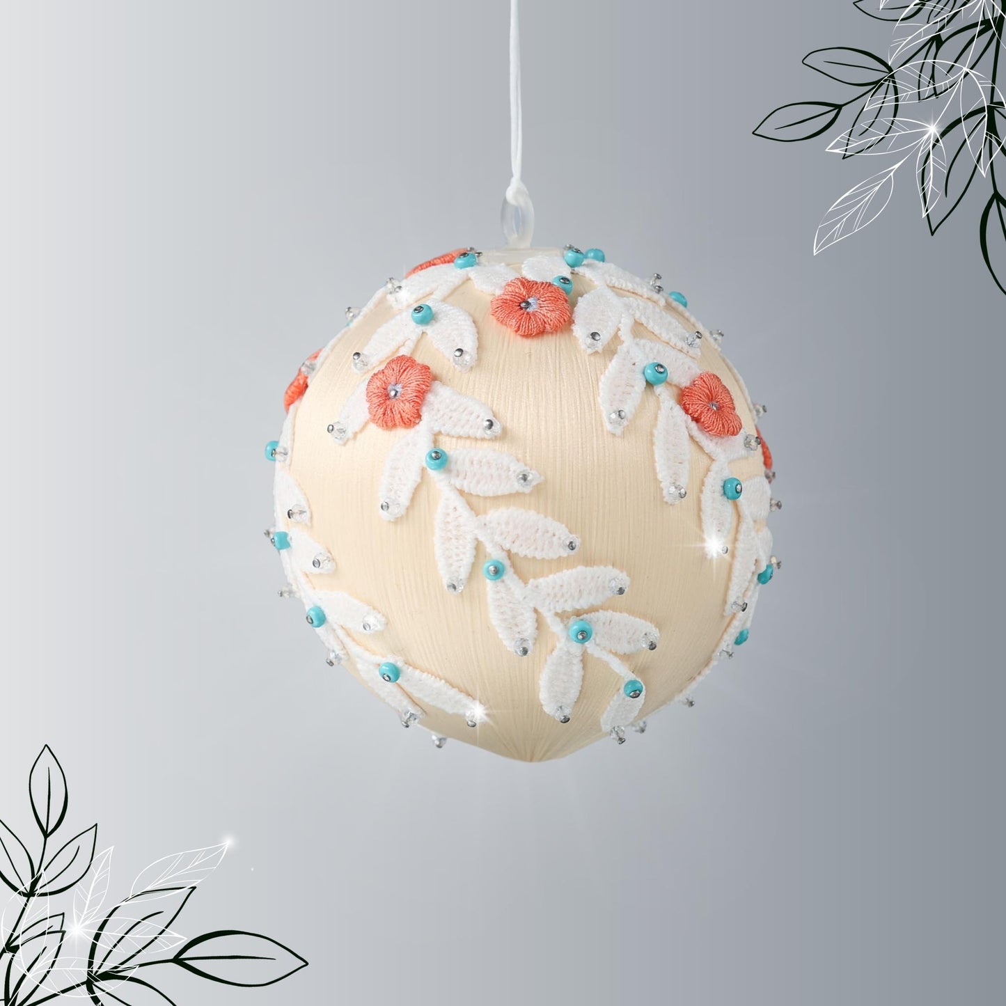 Finished Mid-Century Style Frosted Laurel Satin Ornament in a light tan color with orange embroidered flowers pinned to a satin foam core on a reflective surface by Whim5seasons.