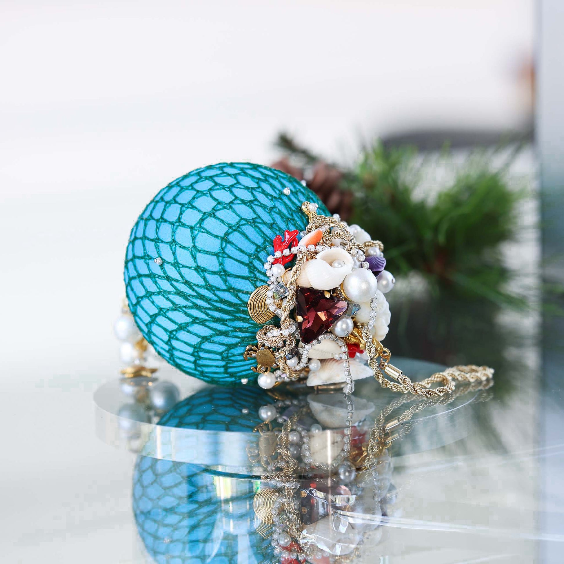 Handmade sequin & beaded blue satin ornament featuring large glass rhinestone, pearls, crab, and anchor charms on a reflective surface by Whim5seasons.